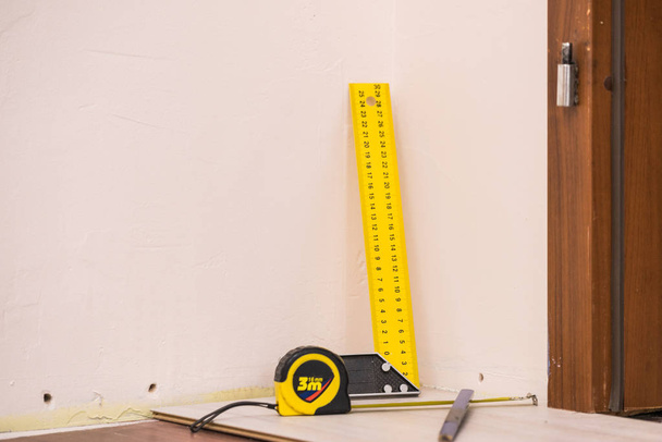 Home renovation concept. Working diy tools. Industrial ruler yellow tape measure, floor panels. - Foto, Imagem