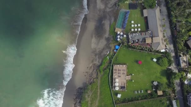 Légi felülről lefelé: homokos strand, szörf és longboard smaragd tenger besétál a szörfösök. Gyönyörű luxus üdülőhely, a tengerparti étterem és a napernyők a sunny paradise island Bali - Felvétel, videó