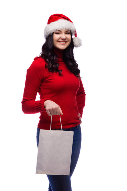 Young brunette woman wearing christmas hat holding present bag with a happy face. Isolated on white background. - Fotografie, Obrázek