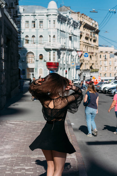 hermosa morena gira, baila en una calle en el centro de la ciudad, ríe, sonríe, felicidad, diversión
 - Foto, Imagen