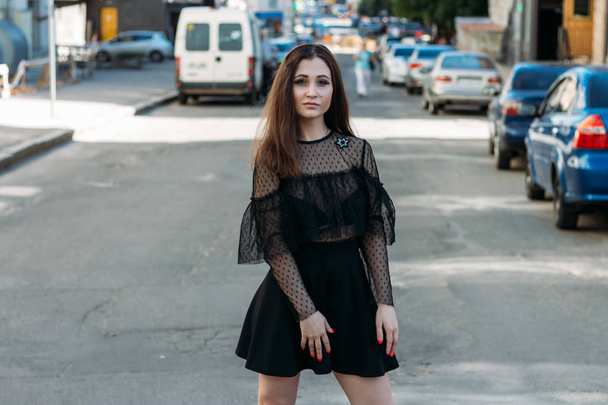 Emotional portrait of Fashion stylish portrait of pretty young woman. city portrait. sad girl. brunette in a black dress with stars and planets on a dress. expectation. dreams. girl - night in the middle of the day - Φωτογραφία, εικόνα