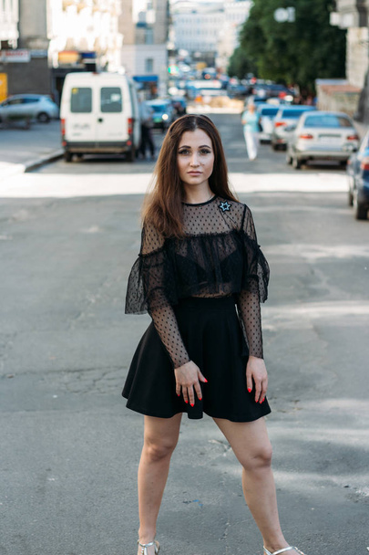 Emotional portrait of Fashion stylish portrait of pretty young woman. city portrait. sad girl. brunette in a black dress with stars and planets on a dress. expectation. dreams. girl - night in the middle of the day - Fotó, kép