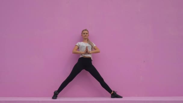 Sportieve jonge vrouw die yoga beoefent geïsoleerd op roze achtergrond - concept van gezond leven en natuurlijk evenwicht tussen lichaam en mentale ontwikkeling. - Video
