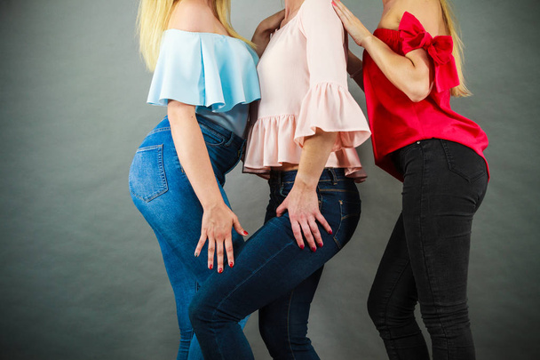Three unrecognizable women having fashionable outfits, blue jeans and colorful shirts. Fashion and clothing concept. - Photo, image