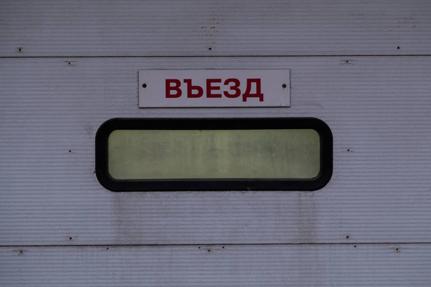 Entrance to the car wash in the car service. Lookout window on the gray roll up plastic door. Inscription on the plate in Russian "Entry" - Fotografie, Obrázek