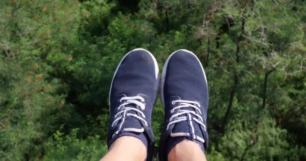 Aerial POV View. Flying over the beautiful forest trees. Aerial camera shot and human legs with blue sneakers in frame. Landscape panorama - Footage, Video
