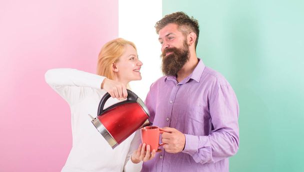 Man with electric kettle and woman with mug ready to drink morning coffee. Enjoying nice morning together. First thing they do every morning prepare hot drink. Get energy charge favourite hot drink - Zdjęcie, obraz