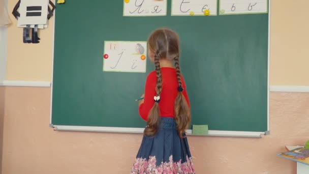 the girl is standing near the blackboard - Video