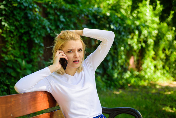 Woman heard bad news. Bad news. Girl blonde tense face talk smartphone green nature background. Woman having mobile phone conversation in park. Girl modern smartphone calling friend cell phone - Photo, image