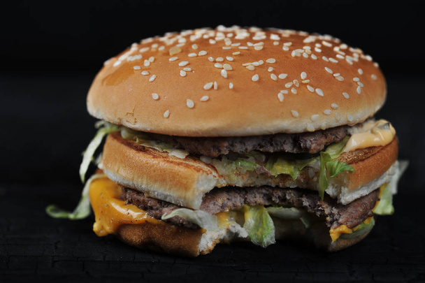 bitten burger on a dark rustic background - Foto, afbeelding