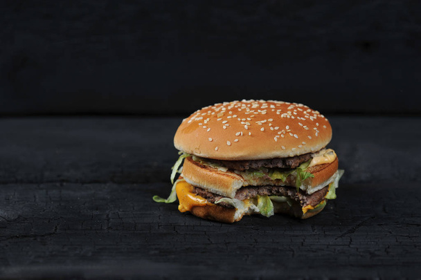 bitten burger on a dark rustic background - Фото, зображення