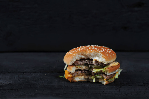 bitten burger on a dark rustic background - Foto, Imagem