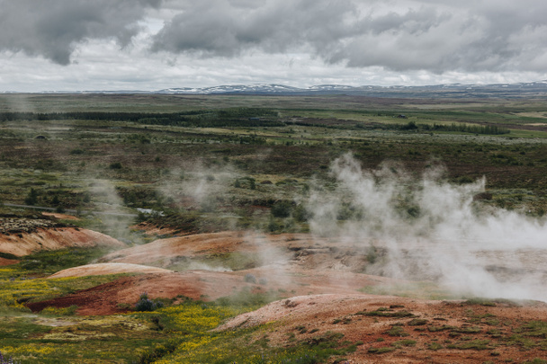 paisaje de vista aérea con respiraderos volcánicos bajo el cielo nublado en el valle de Haukadalur en Islandia
 - Foto, Imagen