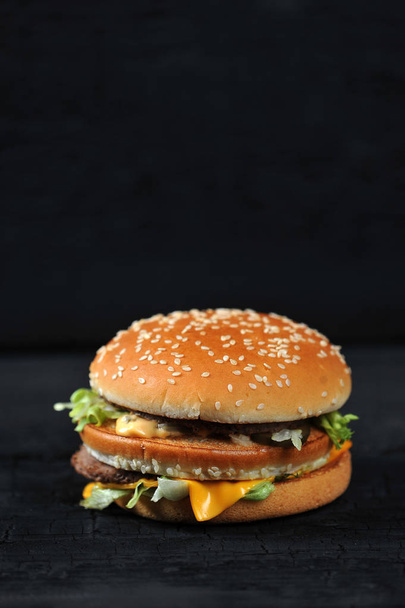 fresh tasty burger on black charcoal background - vertical shot - Foto, afbeelding