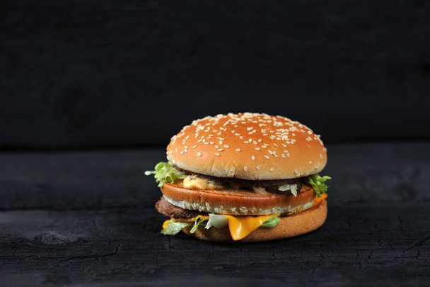 fresh tasty burger on black charcoal background - gorizontal shot - Φωτογραφία, εικόνα