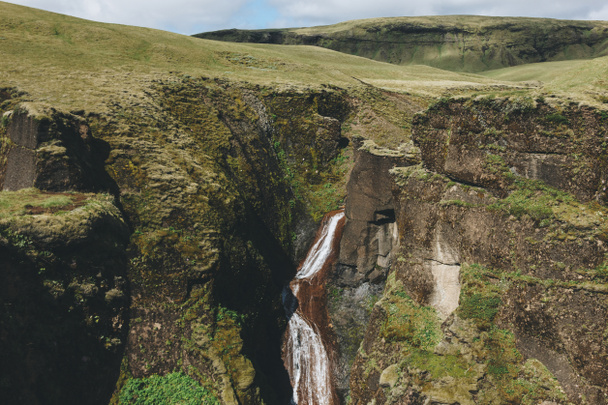 живописный вид реки, текущей с горы с солнечным светом в каньоне Фьядрарглюфур в Исландии
  - Фото, изображение