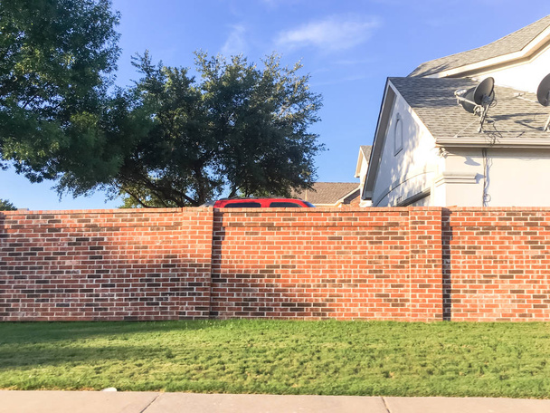 Red brick subdivision walls in Irving, Texas, barrier between neighborhood residential houses and public right-of-way busy street with pathway, satellite tv. Screen, sound, steering walls and fencing - Photo, Image