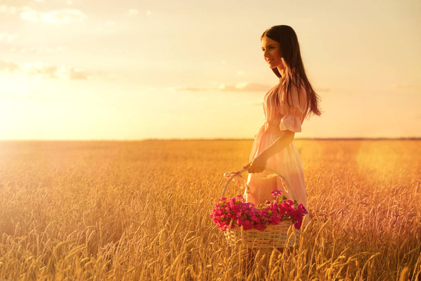 Young woman in wheat field at sunset - Foto, imagen