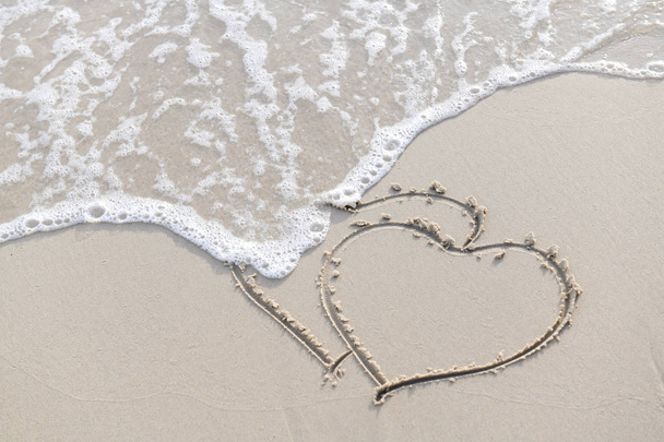 Amor escrevendo na praia junto ao mar pela manhã
 - Foto, Imagem
