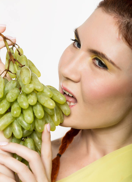 Beautiful redhead woman licks grapes. concept of healthy eating - 写真・画像