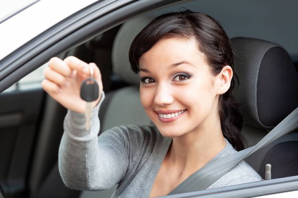 Ευτυχής κάτοχος ενός νέου αυτοκινήτου δείχνει το κλειδί του αυτοκινήτου. Όμορφο κορίτσι οδηγού - Φωτογραφία, εικόνα