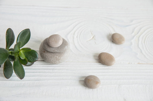 Pyramids of white zen stones with green leaves on wooden background. Concept of harmony, balance and meditation, spa, massage, relax - Photo, image