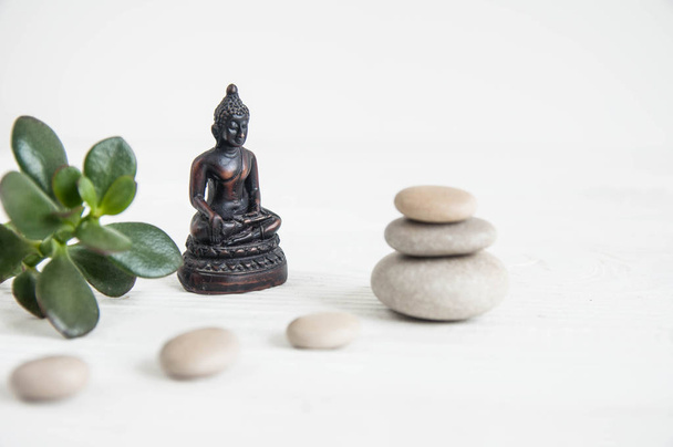 Pyramids of white zen stones with green leaves and Buddha statue. Concept of harmony, balance and meditation, spa, massage, relax - Fotoğraf, Görsel