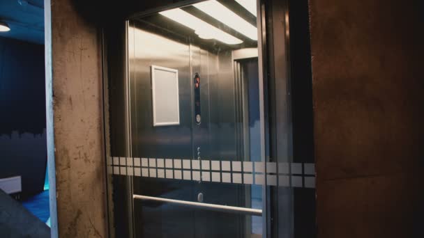 Jovem homem feliz entra no elevador, aperta o botão, a porta fecha e ele monta usando o aplicativo de escritório móvel do smartphone
. - Filmagem, Vídeo