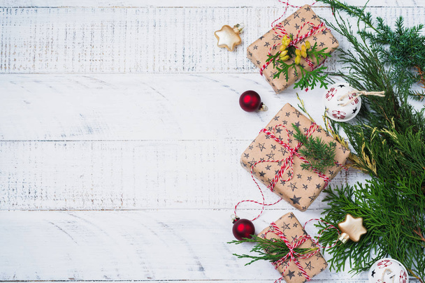 Christmas background with fir branches, toys, gift box and bells on wooden old background table. Selective focus. Top view with copy space. - 写真・画像
