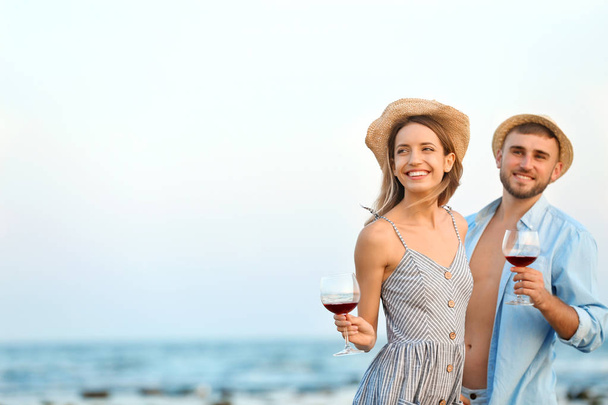 Young couple with glasses of wine on beach - Foto, Imagem