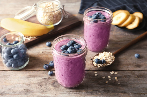 Jars with blueberry smoothies on wooden table - Φωτογραφία, εικόνα