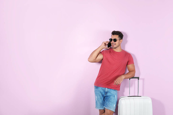 Young man with suitcase on color background. Space for text - Foto, afbeelding