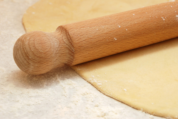 Detail of a wooden rolling pin on rolled out pastry - Foto, Imagen