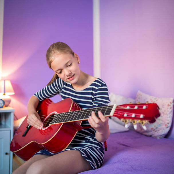Девочка-подросток с гитарой в своей прекрасной комнате
 - Фото, изображение