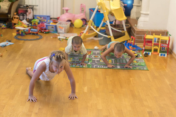 Children make exercises. The concept of a healthy lifestyle. Children's sports. Children are pushed from the floor - Photo, Image