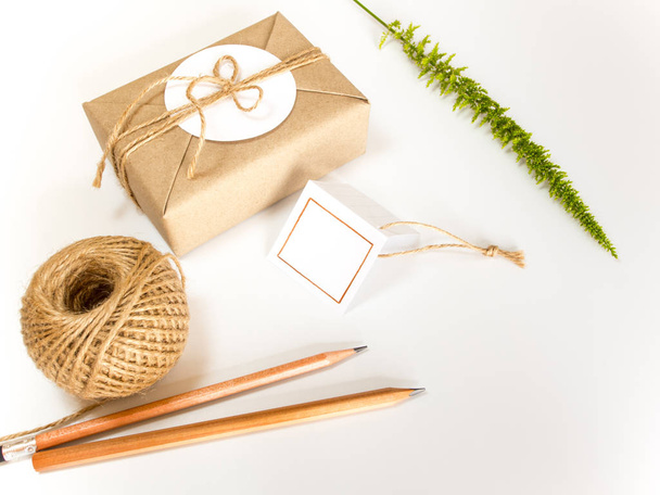 Caja de regalo marrón envuelta en papel kraft y carrete de cuerda de cáñamo rústico como estilo rústico natural con papel y lápiz para escribir su nota
 - Foto, imagen