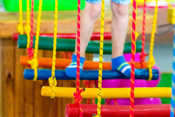 Children's feet  at the playground with swinging bridge. - Foto, afbeelding
