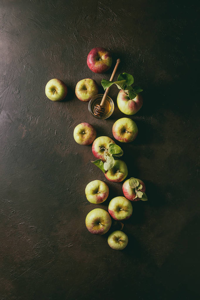 Ripe organic gardening green red apples with leaves and jar of honey over dark texture background. Flat lay, space. Autumn harvest - Фото, изображение