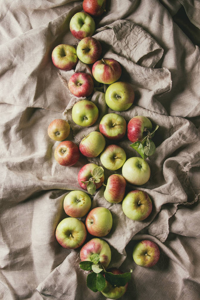 Ripe gardening green red apples with leaves over linen cloth as background. Flat lay, space. Autumn harvest. - Photo, image
