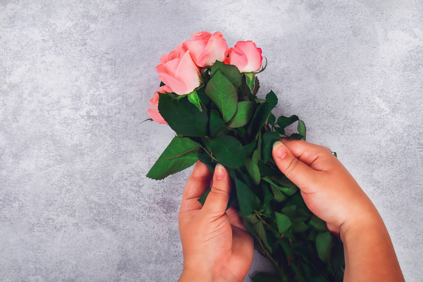 Bouquet of pink roses in the hands of a girl on a light background - Photo, image
