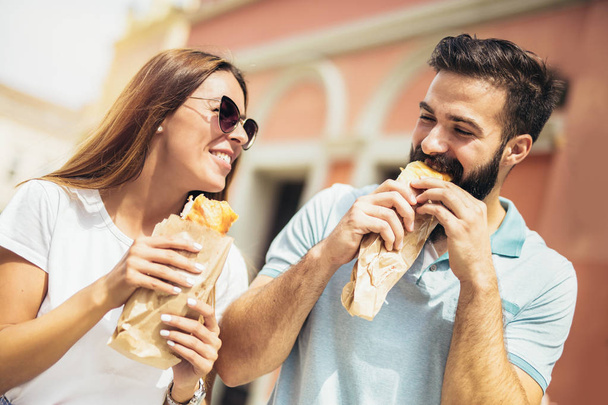 Young couple is eating sandwiches and having a great time - Foto, Bild