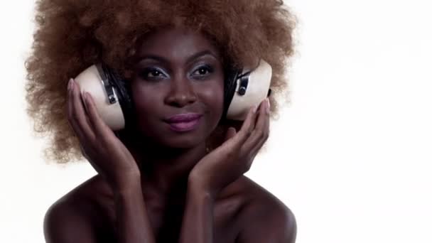 Beautiful African female with large afro wig and headphones - Footage, Video