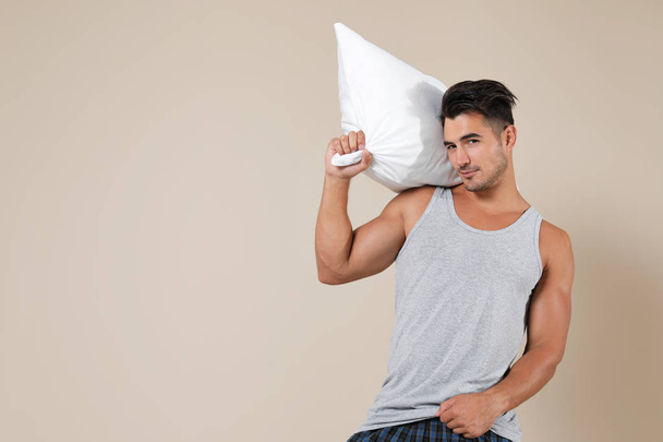 Young man with soft pillow on color background - Fotografie, Obrázek