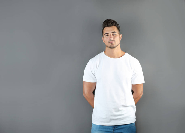 Young man in t-shirt on grey background. Mockup for design - Fotoğraf, Görsel