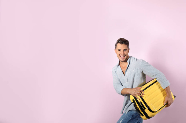 Young man with suitcase on color background. Space for text - Foto, immagini