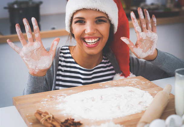 Happy young woman smiling happy having fun with Christmas preparations wearing Santa hat - Foto, imagen