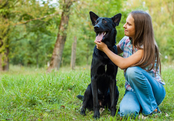Portrait of young teenage girl with a shepherd dog in the park outdoor - Photo, image