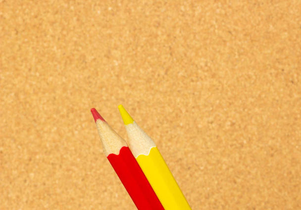 Red and yellow pencils on the background of a cork board, close-up - Φωτογραφία, εικόνα