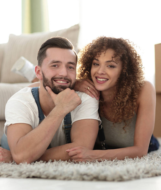 Happy couple lying on the carpet on the blurred background - Photo, Image