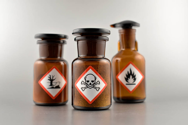 Vial with warning pictogram stock images. Laboratory accessories. Vials on a silver background. Brown glass containers. Brown chemical glass - 写真・画像